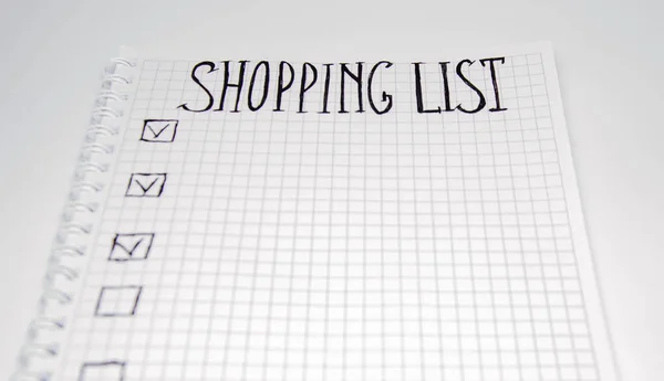 Shopping list. Squared notebook with black pen on a white background. Record ideas, notes, plans, tasks. The list includes bread, milk, bananas. Copy Spase