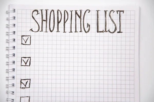 Shopping list. Squared notebook with black pen on a white background. Record ideas, notes, plans, tasks. The list includes bread, milk, bananas. Copy Spase