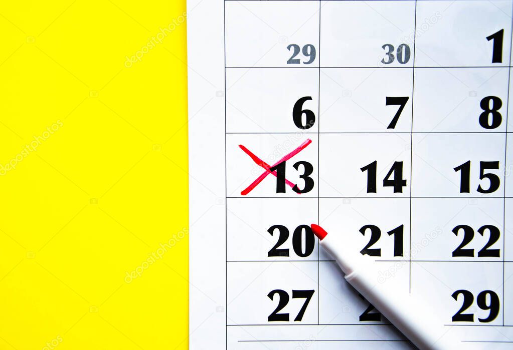 Numbers on the calendar crossed out with a red cross in macro on a yellow background. Calendar for plans, notes, meetings. Business calendar. Marker for notes on the calendar. In the foreground.