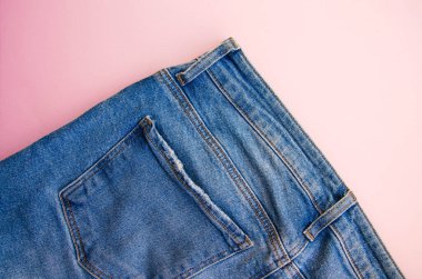 Pembe arka planda kot pantolon. Kot pantolon, cepler, yakın plan dikişler. Yırtık kot pantolon. Boşluğu Kopyala