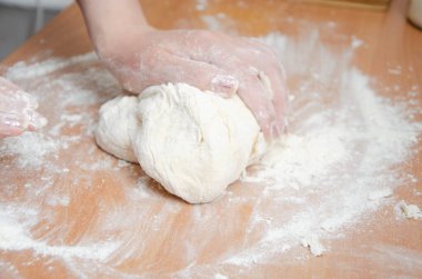 Kadın elleri yoğurur, pizza hamurunu yoğur. Hamur, un, aşçı, pizza. Kız merdane hamuru