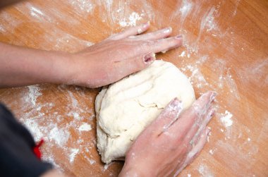 Kadın elleri yoğurur, pizza hamurunu yoğur. Hamur, un, aşçı, pizza. Kız merdane hamuru