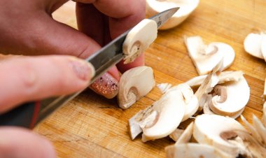 Mantar şampiyonu güvertede doğrandı. Makro mantarlar. El, mantarları bıçakla keser.