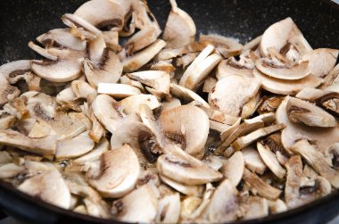 Doğranmış şampiyon mantarları tavada kızartılır. Pizza Mantarı