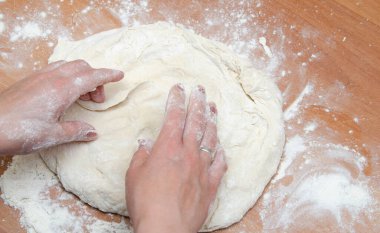 Kadın elleri yoğurur, pizza hamurunu yoğur. Hamur, un, aşçı, pizza. Kız merdane hamuru