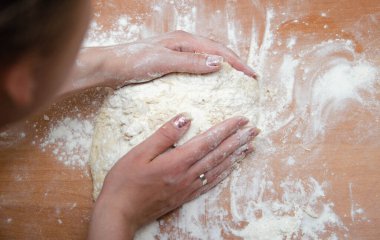 Kadın elleri yoğurur, pizza hamurunu yoğur. Hamur, un, aşçı, pizza. Kız merdane hamuru