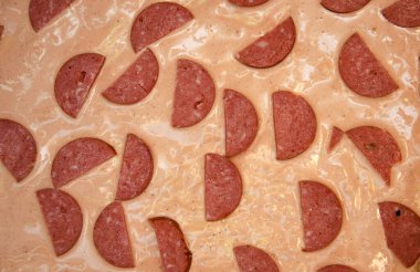 Ev yapımı pizza. Hamurda domates sosu, yarım halka sosis, ızgara mantar, rendelenmiş sert peynir. Çiğ kare pizza.