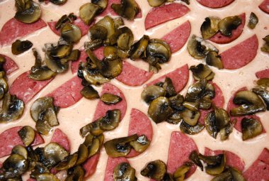 Ev yapımı pizza. Hamurda domates sosu, yarım halka sosis, ızgara mantar, rendelenmiş sert peynir. Çiğ kare pizza.