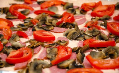 Ev yapımı pizza. Hamurda domates sosu, yarım halka sosis, ızgara mantar, rendelenmiş sert peynir. Çiğ kare pizza.