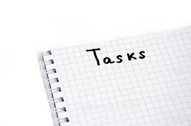 Beyaz arka planda kafesin içinde spiral çizilmiş bir defter. Defterin üstünde siyah kalemli görevler yazılıdır. Üst görünümü not et. Not Parçacığı