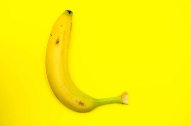 Sarı arka planda bir muz manzarası. Dövülmüş, çizilmiş, çürük bir muz. Taşımacılık izleri taşıyan sarı muz, çürük, hasar, yalanlar solda biter.