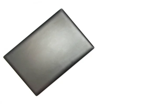 Beyaz arka planda kapalı bir laptop. Yukarıdan bak. Dizüstü bilgisayar sol üst köşede yan yatar. Siyah, grafit, gri, koyu dizüstü bilgisayar