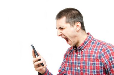 Beyaz arka planda akıllı telefonu olan ekose gömlekli genç bir adam. Adam onun önünde akıllı bir telefon tutuyor ve ona bağırıyor. Öfke, telefon görüşmesi sırasında çığlık atmak.