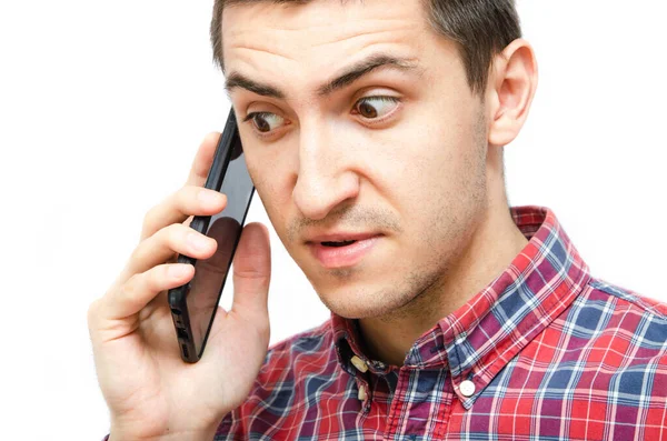 Beyaz arka planda akıllı telefonu olan ekose gömlekli genç bir adam. Adam akıllı telefonu kulağından tutup, telefonla konuşuyordu. Bir telefon konuşmasında öfke, öfke, şaşkınlık, dikkat.