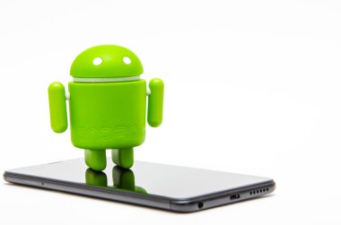 Android biblo ve akıllı telefon. Ekolojik plastikten yapılmış yeşil android heykeli siyah bir akıllı telefonun üzerinde duruyor.