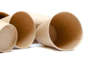 Kahve, çay için kahverengi kağıt bardak, beyaz arka planda çevresel malzemelerden bir içecek. Bir sürü bardak. Gözlükler bir halka şeklinde daire şeklinde yan yatar. Ön ve üst manzara. Makro, boş bardaklar