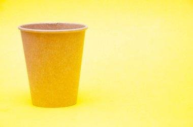 Kahve, çay için kahverengi kağıt bardak, sarı arka plandaki çevresel malzemelerden bir içecek. Sağ tarafta makroda küçük bir fincan var. Ön görünüş ve üst görünüm, alt görünüm. Metni sola yerleştir