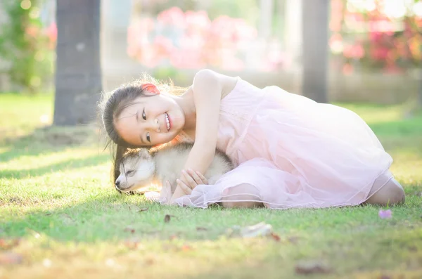 Sian dívka si hraje s sibiřský husky štěně — Stock fotografie