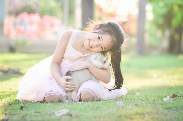 Sian meisje speelt met Siberische husky puppy — Stockfoto