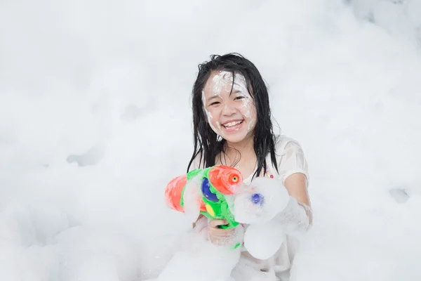 Pequeña chica asiática sonriendo y sosteniendo pistola de agua —  Fotos de Stock