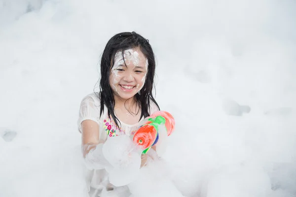 Pequeña chica asiática sonriendo y sosteniendo pistola de agua — Foto de Stock