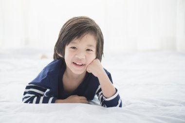 Asyalı çocuk beyaz yatakta yatarken