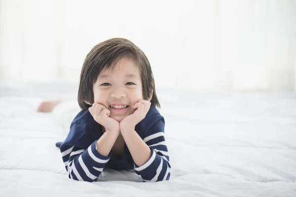 Asian child lying on white bed — Stock Photo, Image