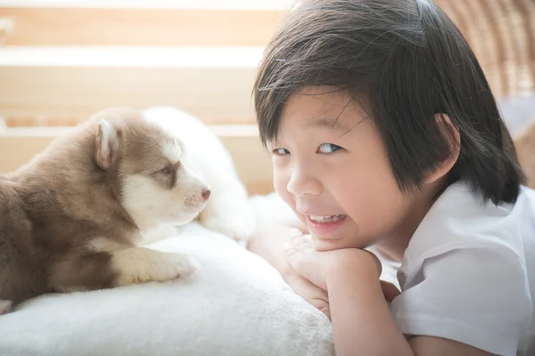 Aziatische kind spelen met Siberische husky puppy — Stockfoto