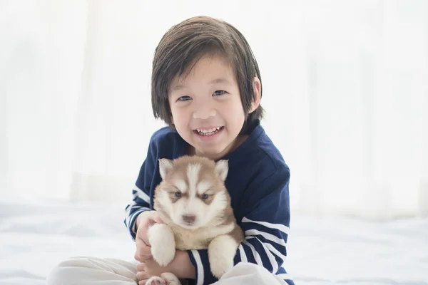 Asiático criança e siberiano husky filhotes deitado — Fotografia de Stock