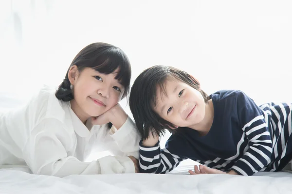 Ασίας τα παιδιά που βρίσκονται σε λευκό κρεβάτι — Φωτογραφία Αρχείου