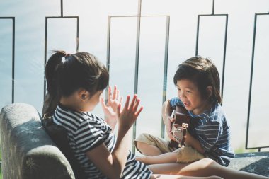 Asyalı kız ukulele pencerenin iskambil 