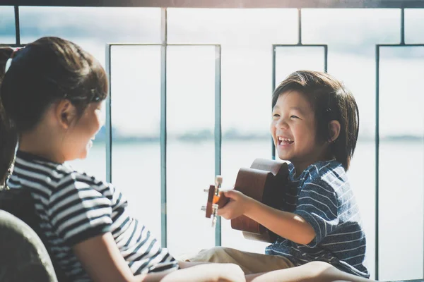 Asyalı kız ukulele pencerenin iskambil — Stok fotoğraf