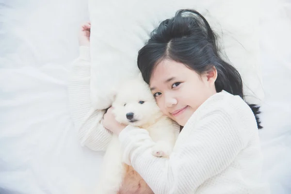 Asian girl lying with siberian husky puppy on be — Stock Photo, Image