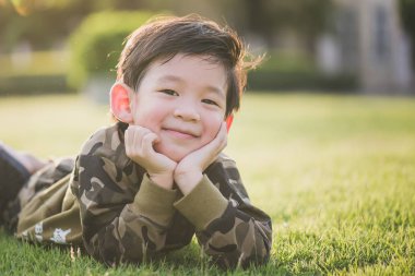 Şirin Asyalı çocuk greeen çim üzerinde yalan 
