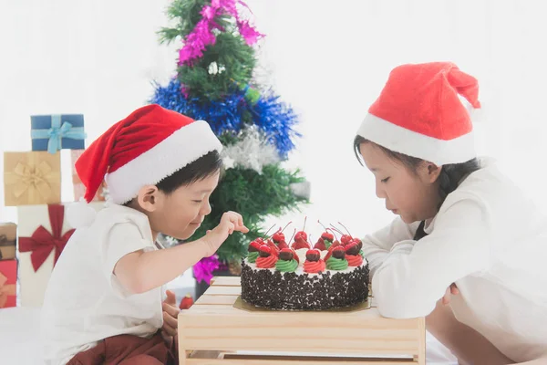 Gelukkige Aziatische kinderen in kerstmuts met kerst cake — Stockfoto