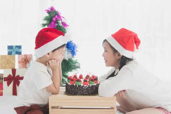 Glada asiatiska barn i jul hatt med julkaka — Stockfoto