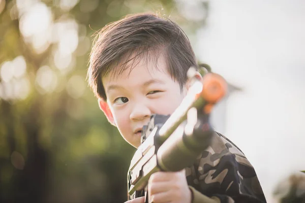 Cute Asian dziecko w żołnierz jednolite, gry zabawki pistolet na zewnątrz — Zdjęcie stockowe