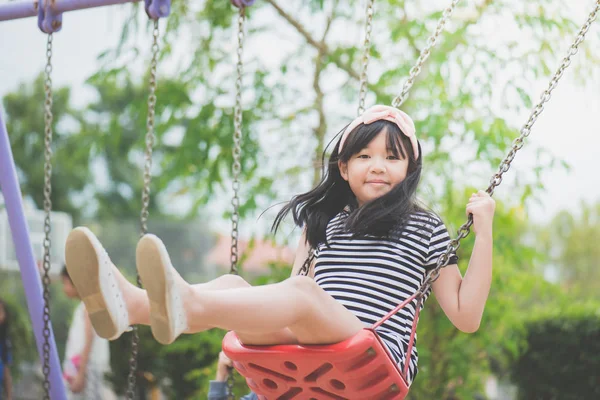 Азіатська дівчина гойдається на дитячому майданчику — стокове фото