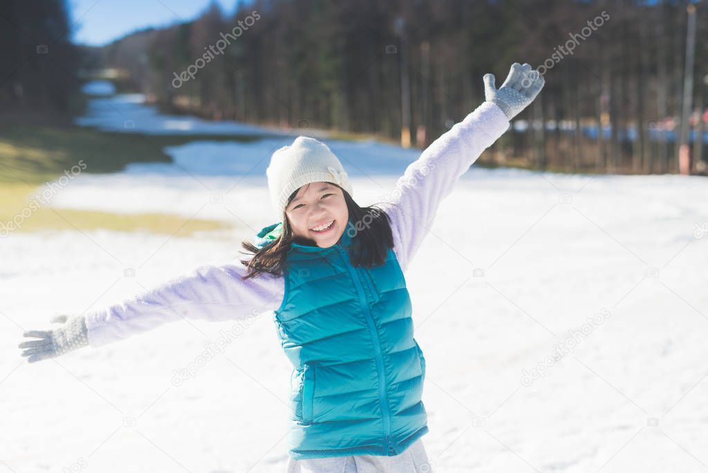 Happy asian girl smiling outdoors in snow on cold winter day