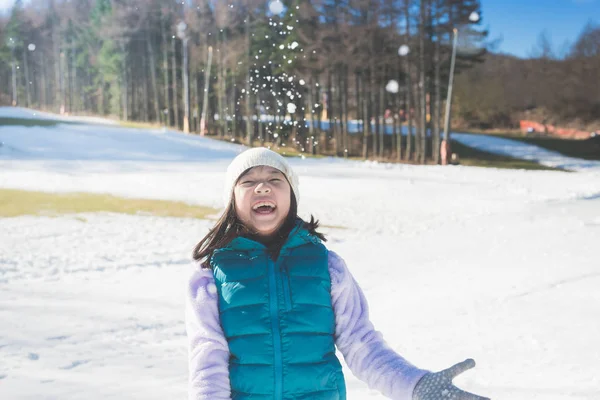 Heureuse fille asiatique souriant en plein air dans la neige sur la journée froide d'hiver — Photo