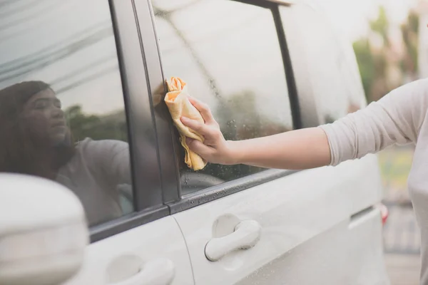 Kobieta mycia samochodu okno szmatką z mikrofibry — Zdjęcie stockowe