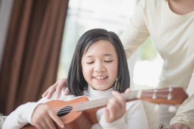 Ukulele wiyh onun morther oynayan kız