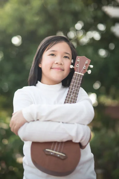 Ásia menina jogar ukulele ao ar livre retrato — Fotografia de Stock