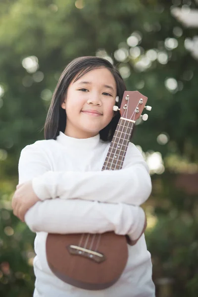 Ásia menina jogar ukulele ao ar livre retrato — Fotografia de Stock