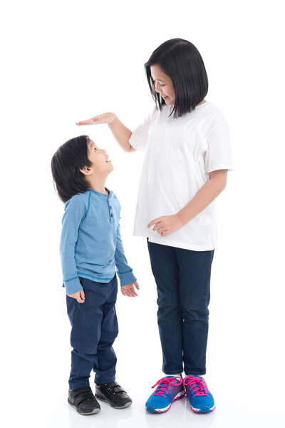 Asiangirl measures the growth of her brother on white background isolated