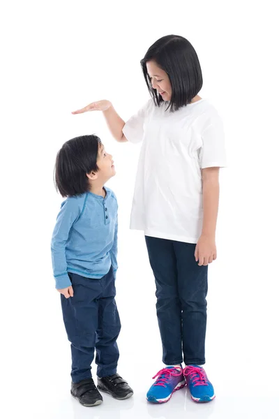 Asiangirl mede o crescimento de seu irmão no fundo branco isolado — Fotografia de Stock