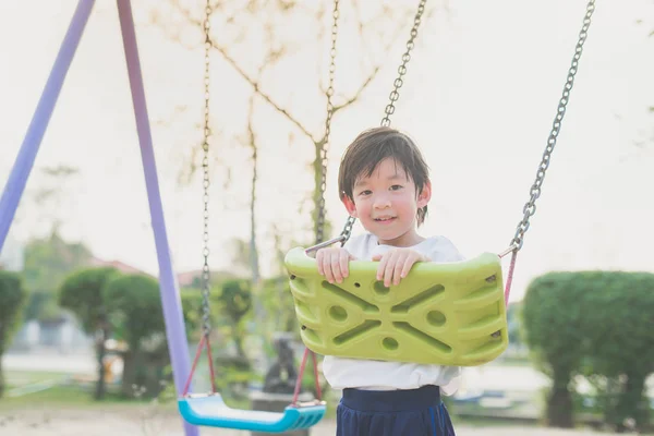 Asiatiska barn som leker på swing — Stockfoto