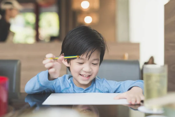 アジアの子が白い紙に書く — ストック写真