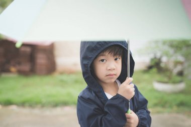 Parkta oynarken renkli şemsiye tutan mutlu Asyalı çocuk 