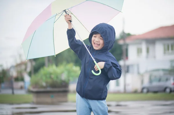 Happy asian boy holding colorful umbrella playing in the park — Stock Photo, Image